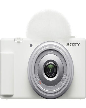 Front view of white Sony ZV 1F vlog camera with 20mm f/2.0 lens and top windscreen attached.