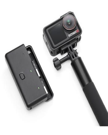 DJI Osmo Action 5 Pro on extension grip beside dual battery charging case