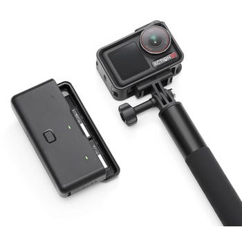 DJI Osmo Action 5 Pro on extension grip beside dual battery charging case