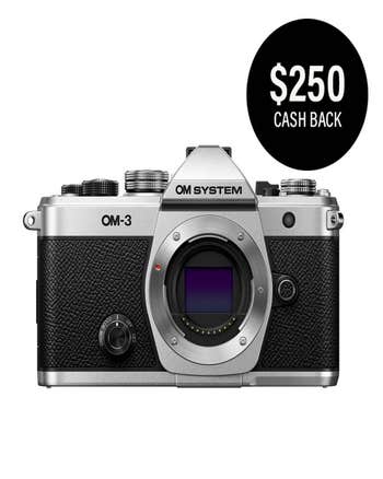 OM System OM-3 silver mirrorless camera body front view with $250 cashback offer