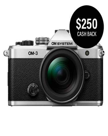 OM System OM-3 silver camera with 12-45mm lens, close front view, $250 cashback badge