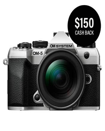 OM System OM-5 Mark II silver mirrorless camera with 12-45mm lens, front view and $150 cash back badge.