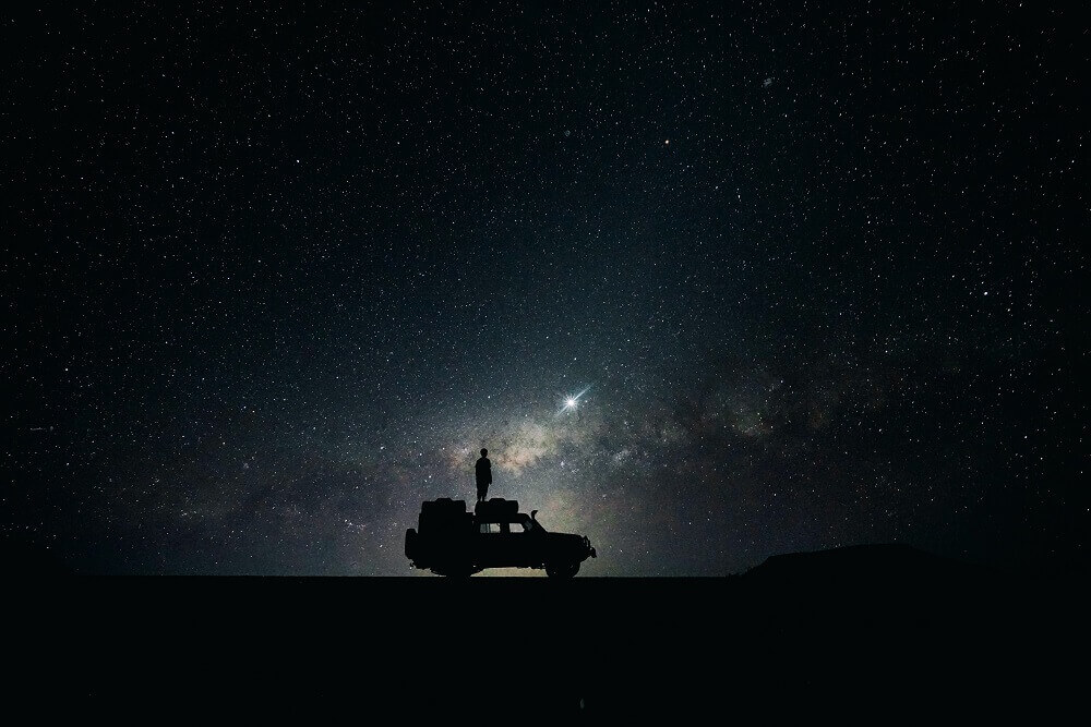 Silhouette of a man standing on a truck with stars on the background