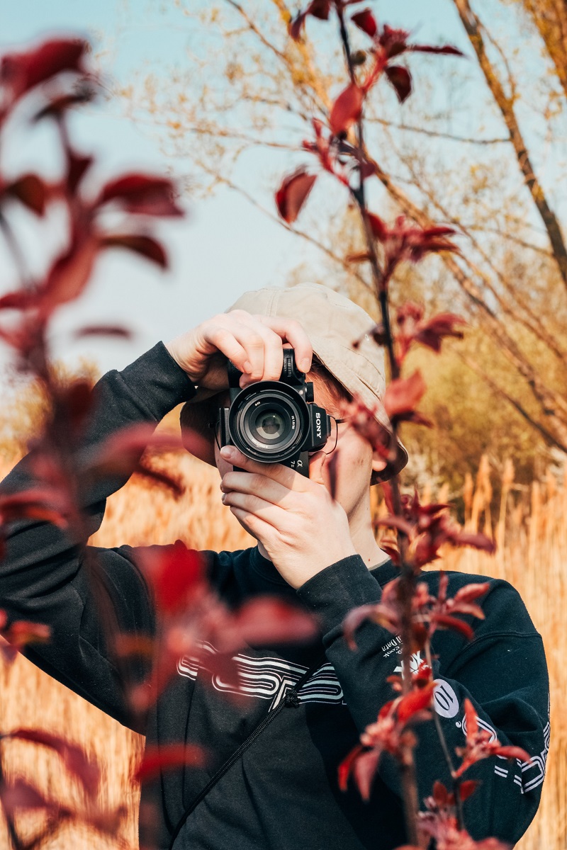 man looking through the viewfinder of a sony mirrorless camera