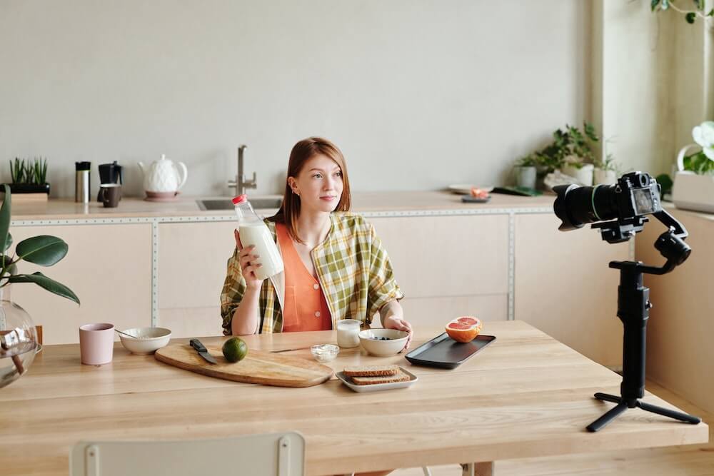 Woman holding a bottle of milk while in front of a camera